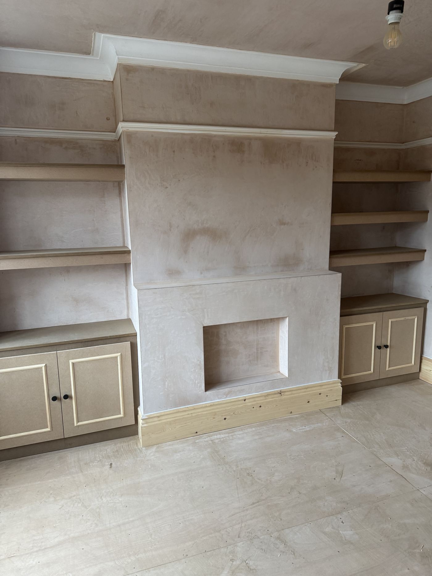 Fitted alcove shelving and cupboards either side of a chimney breast